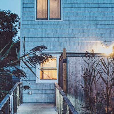 evening view of a blue beach house with the lights on